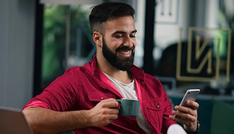 Man drinking coffee and looking at mobile phone